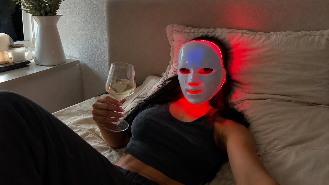 Woman relaxing in bed wearing the Lumino red light LED face mask